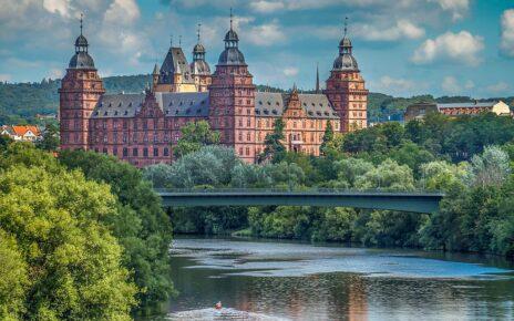 Im Hintergrund das Schloss Johannisburg in Aschaffenburg. In Bildmitte der Main mit der Willigesbrücke. Im weiteren Verlauf der Main mit einem Baum links am Bildrand