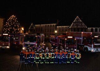 Festlich geschmückte Fahrzeuge der Feuerwehr Großostheim. Im Hintergrund das Nöthigsgut am Großostheimer Marktplatz. Davor stehen die Mitwirkenden der Feuerwehr Großostheim