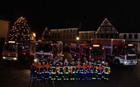 Festlich geschmückte Fahrzeuge der Feuerwehr Großostheim. Im Hintergrund das Nöthigsgut am Großostheimer Marktplatz. Davor stehen die Mitwirkenden der Feuerwehr Großostheim