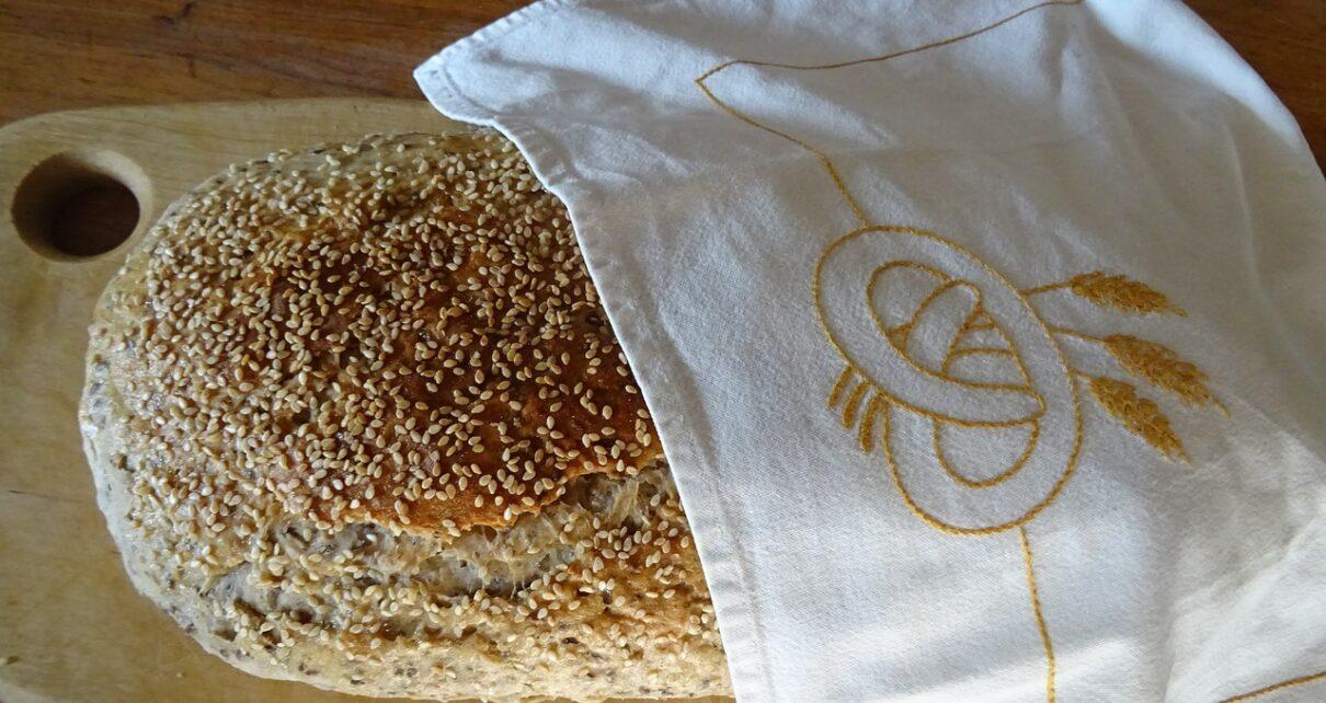 Ein Laib Brot auf einem Brett halb bedeckt mit einem Tuch