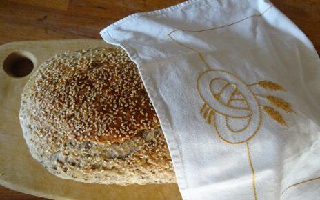 Ein Laib Brot auf einem Brett halb bedeckt mit einem Tuch