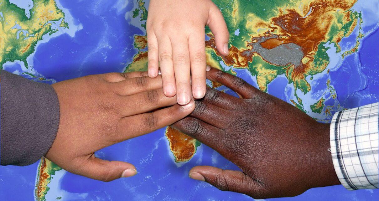 Migration 3 Hände der verschiedenen Hautfarben auf einer bunten Weltkarte