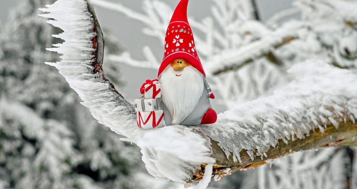 Ein kleiner Weihnachtsmann sitzt auf einem zugeschneiten Zweig