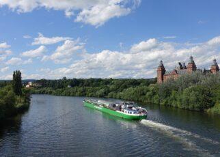 Blick auf den Main mit einem Schiff, im Hintergrund das Aschaffenburger Schloss