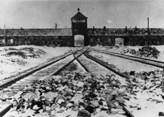 Konzentrationslager Auschwitz, Polen 1945. Lagertor (innen) / Ausfahrt nach der Befreiung, im Vordergrund von den Wachmannschaften zurückgelassene Ausrüstungsgegenstände.