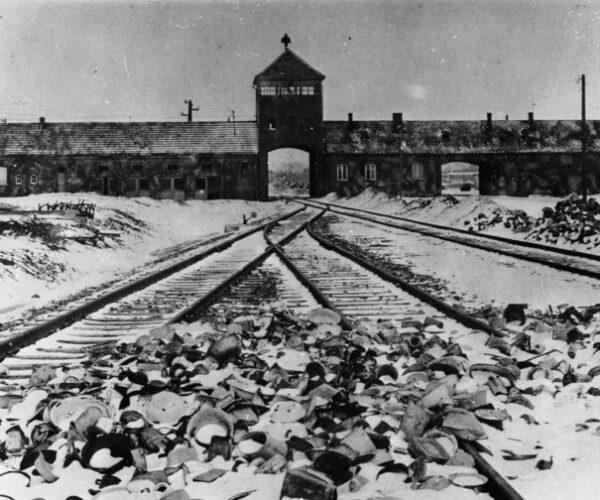 Konzentrationslager Auschwitz, Polen 1945. Lagertor (innen) / Ausfahrt nach der Befreiung, im Vordergrund von den Wachmannschaften zurückgelassene Ausrüstungsgegenstände.