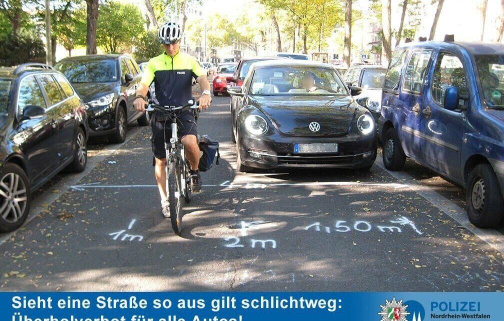 Rechts und Links parkende Autos, PKW versuchen Radfahrende zu überholen, kein Abstand von 1,5 Meter möglich