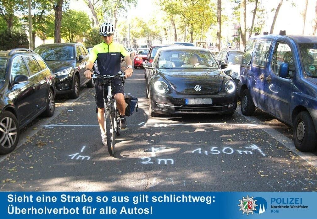 Rechts und Links parkende Autos, PKW versuchen Radfahrende zu überholen, kein Abstand von 1,5 Meter möglich