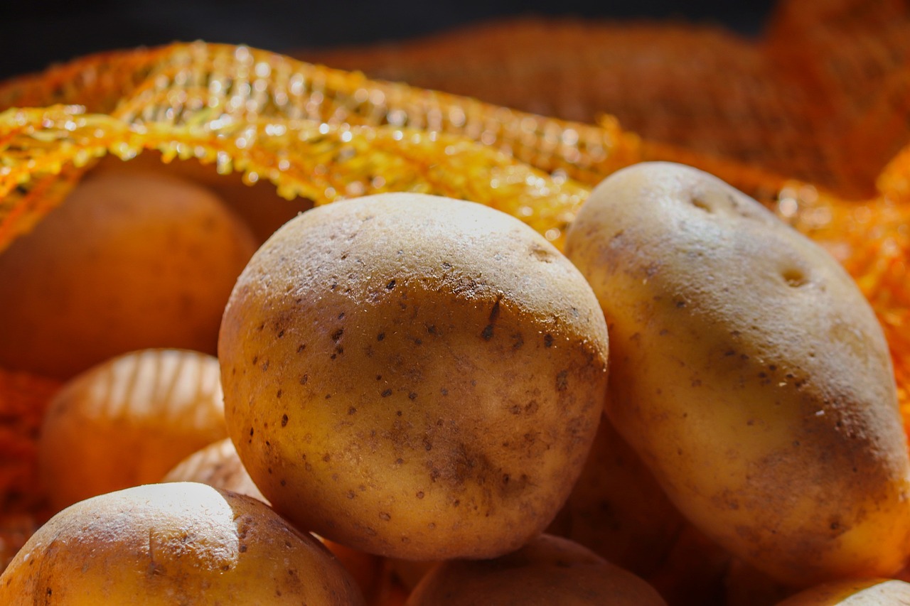 Kartoffeln, die vor einem Kartoffelsack liegen